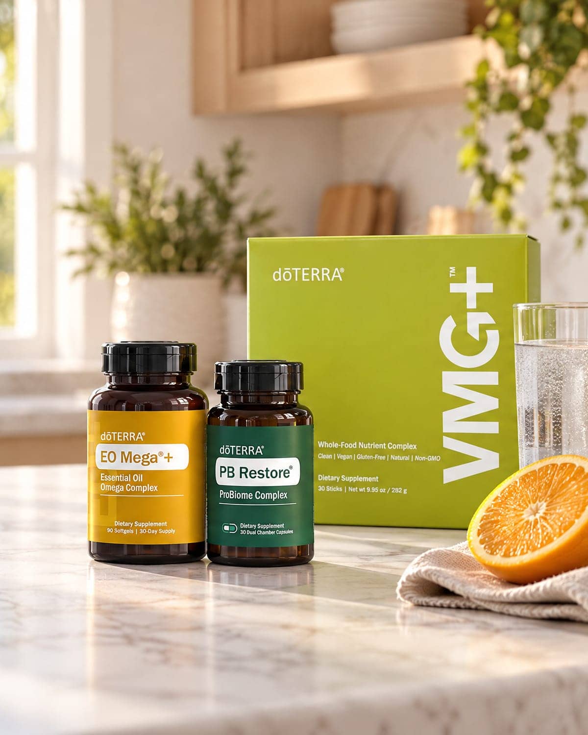 The three products of the Foundational Wellness Bundle on a sunlit marble kitchen counter beside a glass of iced water and a halved orange
